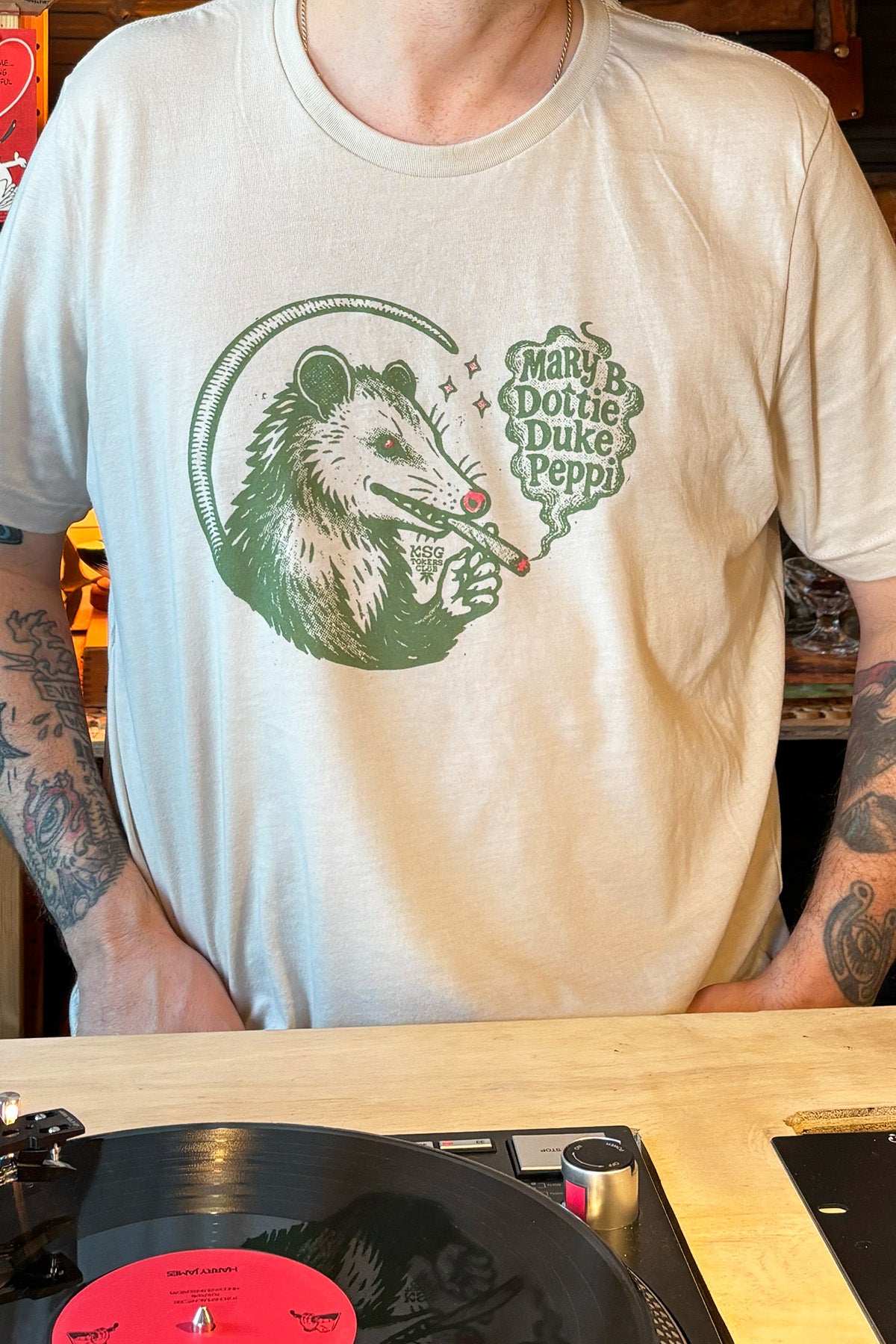 Kin Ship Goods Tokers Club T-shirt with possum illustration and biscuit sandwich names Mary B., Dottie, Duke, and Peppi.