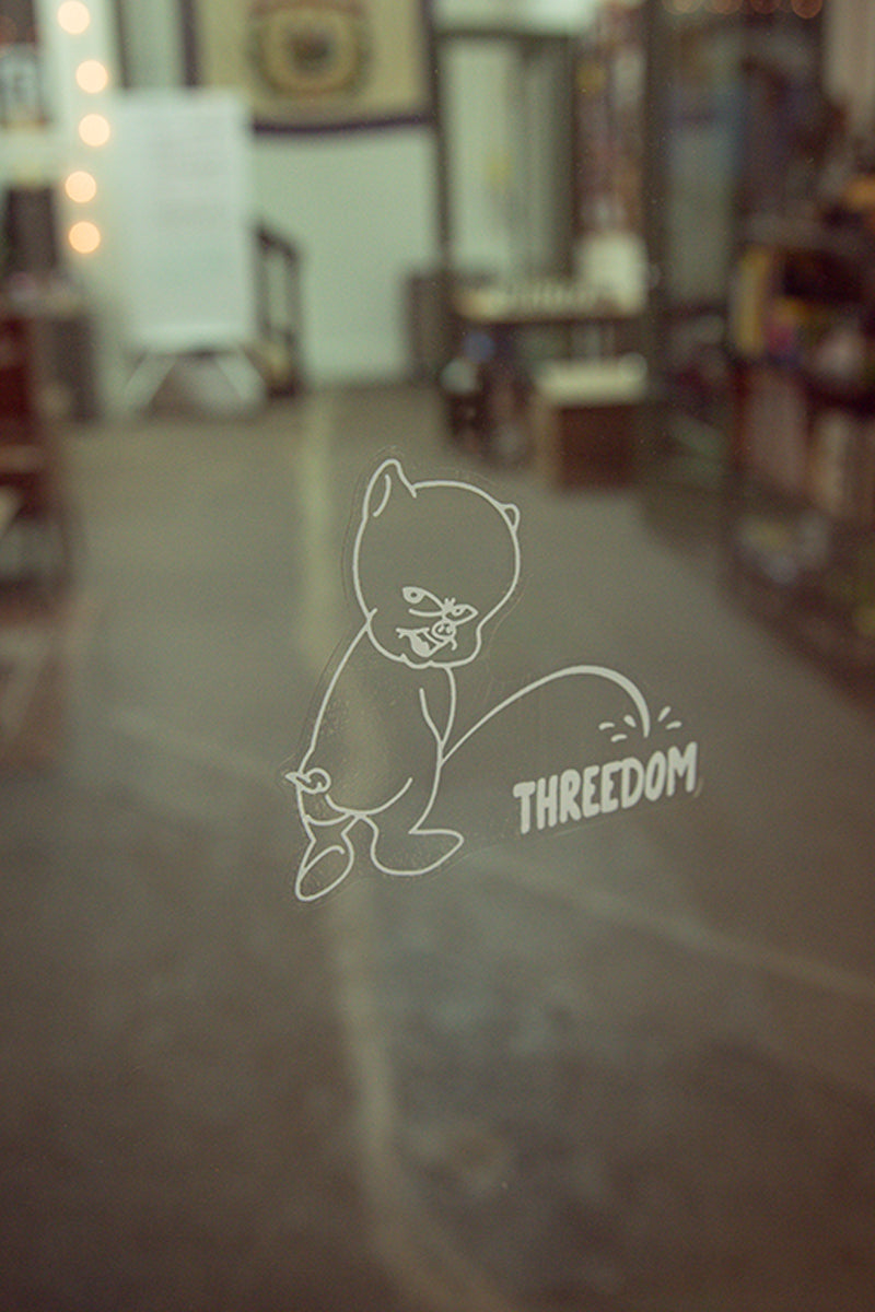 Threedom podcast decal from Kin Ship Goods – parody design featuring a pig peeing on the logo, inspired by classic car decals. Perfect for fans of the show.