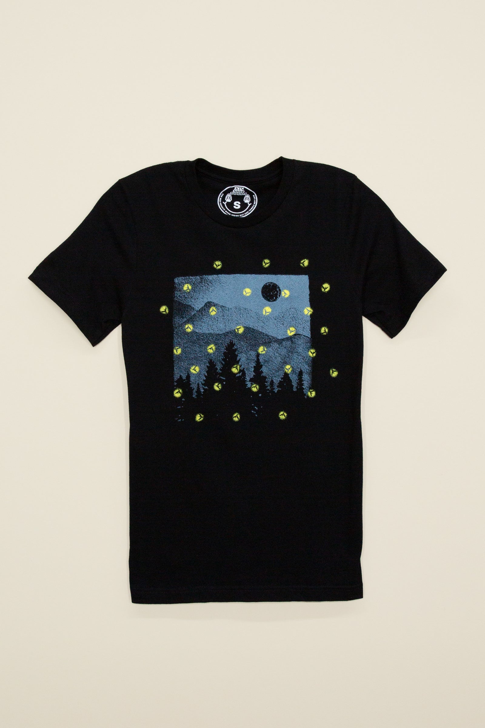 Kin Ship Goods Firefly Tee with hand-printed glow-in-the-dark fireflies over a forest landscape on black cotton blend shirt