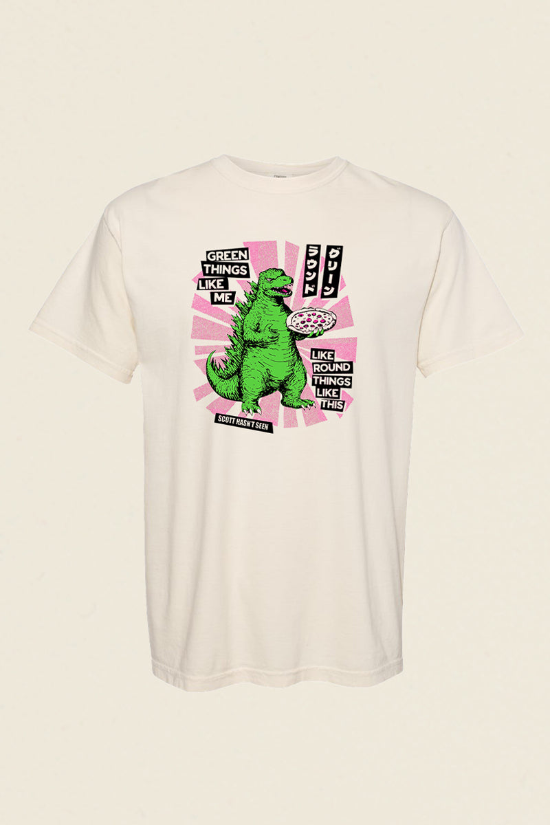Kin Ship Goods x Comedy Bang Bang tee featuring a green dinosaur holding a pizza with comic-style text: "Green things like me like round things like this.