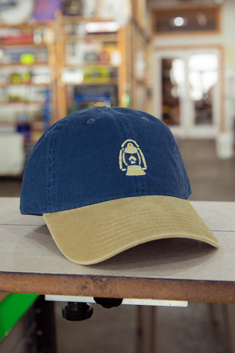 Kin Ship Goods lantern hat with navy crown and khaki brim—embroidered Appalachian lantern logo on classic cotton dad cap.