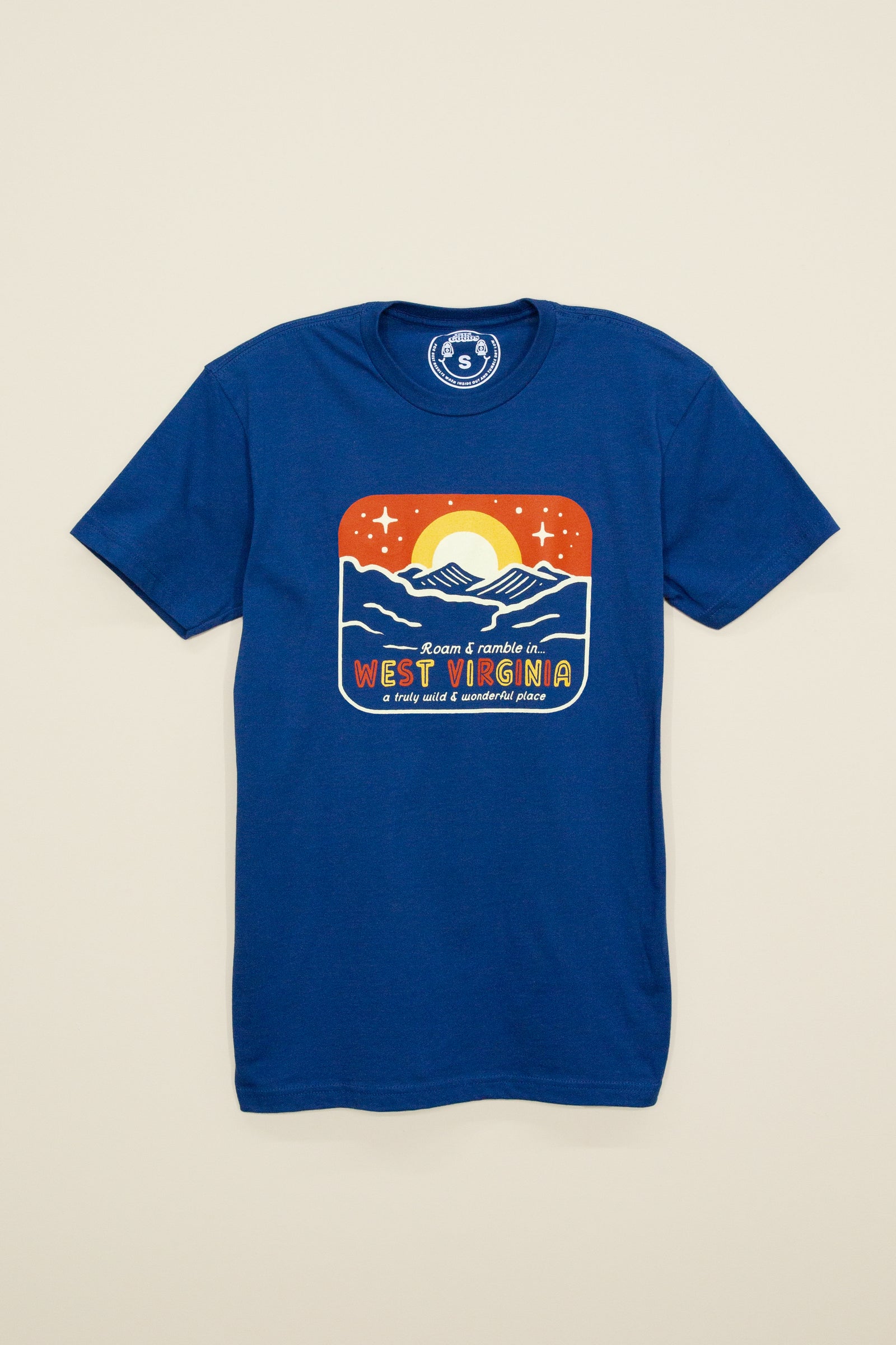 Kin Ship Goods royal blue tee with retro sunset and mountain graphic reading ‘Roam & Ramble in West Virginia, a truly wild & wonderful place.’