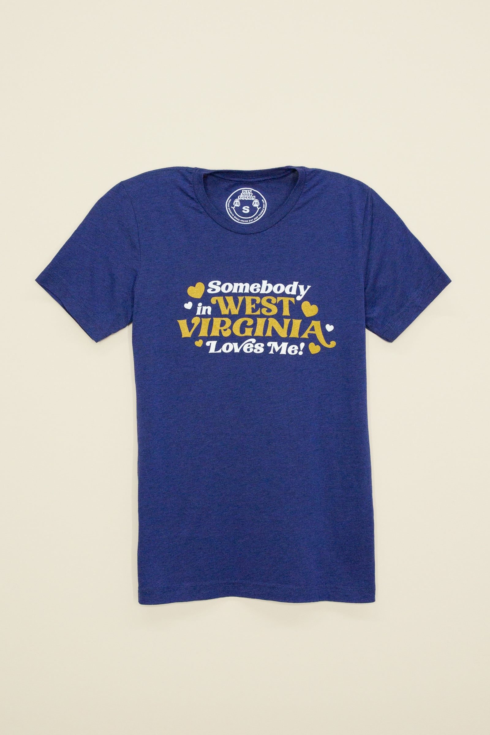 Kin Ship Goods adult tee in heather blue with gold and white ‘Somebody in West Virginia Loves Me!’ retro-style graphic.